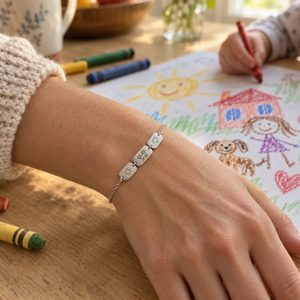 A parent wearing an engraved motifs bracelet while a child draws at the kitchen table