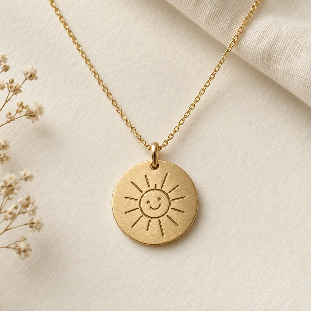 Gold-tone disc necklace engraved with a child’s smiling sun drawing